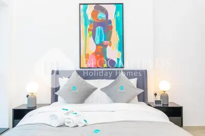 a bedroom with a bed with white sheets and pillows at Bloomfields Stylish 1br Orchid Residence in Dubai