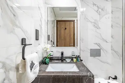 a white bathroom with a sink and a mirror at Chic Studio Living JVC in Dubai
