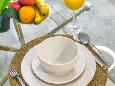 a table with a bowl of fruit and a cup of juice at Chic Studio Living JVC in Dubai