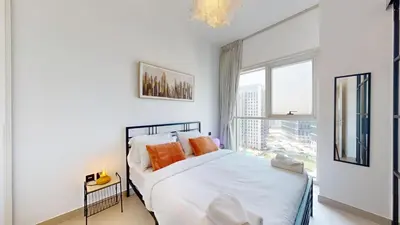 a white bedroom with a bed and a window at Cozy and Modern 1BR in Dubai Hills in Dubai