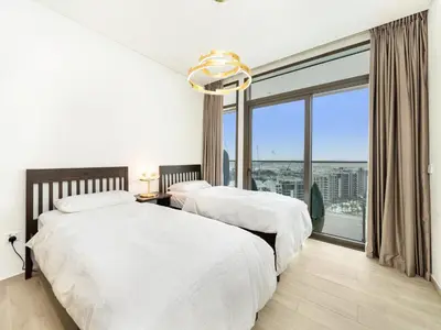 two beds in a bedroom with a large window at Palace residence creek harbour in Dubai