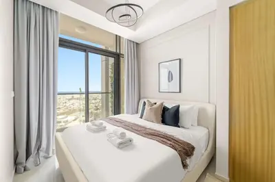 a white bedroom with a large bed and a window at Silkhaus Elite 2BR near Safa Park in Aykon City in Dubai