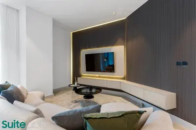 a living room with a couch and a tv on a wall at Luxe 2 Bedroom with Burj Khalifa and Canal Views in Dubai