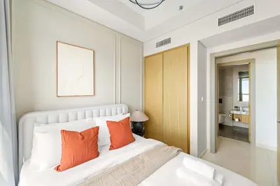 a bedroom with a white bed with orange pillows at Silkhaus Spacious 2BR in Aykon City Near Safa Park in Dubai