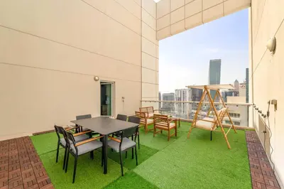a table and chairs on a balcony with green grass at Silkhaus Homey 2BR at Mayfair Tower in Business Bay in Dubai