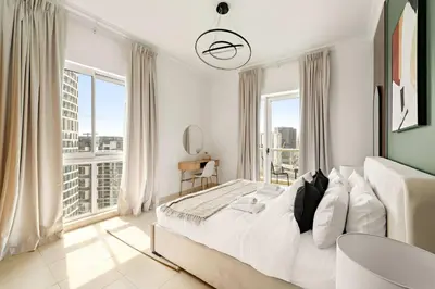 a white bedroom with a large bed and large windows at Silkhaus Homey 2BR at Mayfair Tower in Business Bay in Dubai