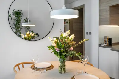 a vase of flowers on a table with a mirror at The Designers Apartment Dubai Marina in Dubai