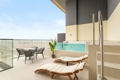 a patio with a table and chairs and a pool at VayK - Luxury 2BR with Jacuzzi in JVC in Dubai
