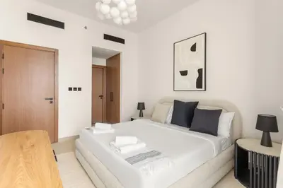 a white bed in a white room with a couch at VayK - Luxury 2BR with Jacuzzi in JVC in Dubai