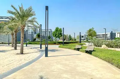 a park with benches and palm trees and a building at Luxury 1BR with Aquatic View, District One in Dubai
