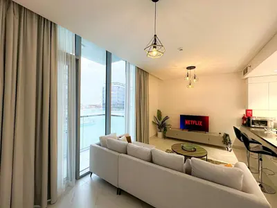 a living room with a couch and a large window at Luxury 1BR with Aquatic View, District One in Dubai