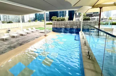 a swimming pool with an umbrella in a building at Burj Khalifa View Luxury Apt - 7 min to Dubai Mall in Dubai