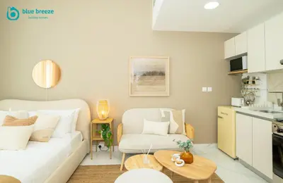 a living room with a white couch and a table at Blue Breeze - Elegant Studio in Serenity Lake 5, JVC in Dubai
