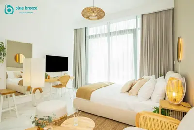 a white bedroom with a large bed and a desk at Blue Breeze - Elegant Studio in Serenity Lake 5, JVC in Dubai