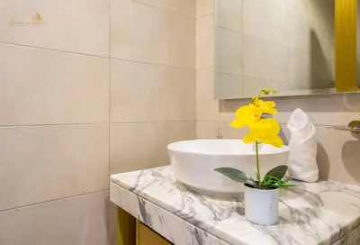 a bathroom with a sink and a yellow flower on a counter at Magnificent Canal View 2 Bhk 6 pax in Dubai