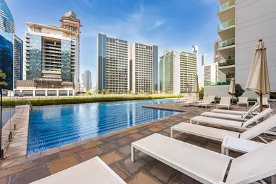 a swimming pool with chaise lounge chairs and buildings at Apartment in Downtown Dubai in Dubai