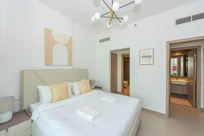 a white bedroom with a large white bed in it at Vayk - Spacious 1BR Apartment in Dubai Hills in Dubai