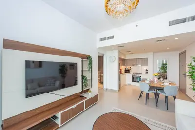 a living room with a large flat screen tv on the wall at Vayk - Spacious 1BR Apartment in Dubai Hills in Dubai