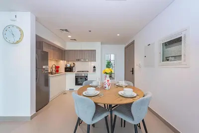 a kitchen and dining room with a wooden table and chairs at Vayk - Spacious 1BR Apartment in Dubai Hills in Dubai