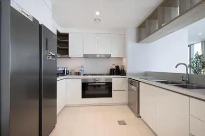 a kitchen with white cabinets and a stainless steel refrigerator at Luxury Stay Burj Views and Direct Dubai Mall Access in Dubai
