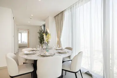 a white dining room with a table and chairs at Luxury Stay Burj Views and Direct Dubai Mall Access in Dubai