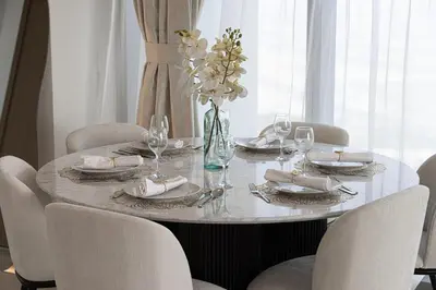 a dining room table with chairs and a vase of flowers at Luxury Stay Burj Views and Direct Dubai Mall Access in Dubai