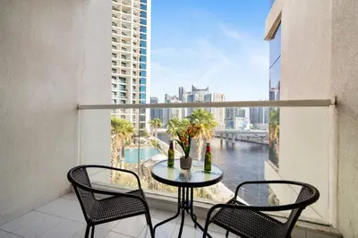 a table and chairs on a balcony with a view of a river at Damac Maison Prive, Lake View - Free Parking in Dubai