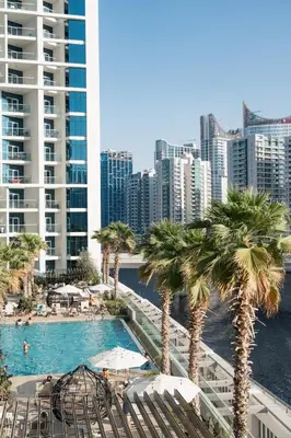 a view of a pool with palm trees and buildings at Damac Maison Prive, Lake View - Free Parking in Dubai