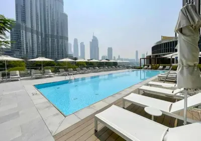 a swimming pool with chairs and umbrellas on a building at Maison Privee - Exclusive Apt with Unmatched Burj Khalifa Views in Dubai