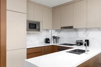 a white kitchen with a sink and a microwave at Maison Privee - Exclusive Apt with Unmatched Burj Khalifa Views in Dubai