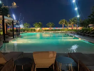 a large swimming pool at night with chairs and tables at Panorama Sea & Sunset View 2 BHK in Dubai