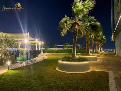 a park with palm trees and a building at night at Panorama Sea & Sunset View 2 BHK in Dubai