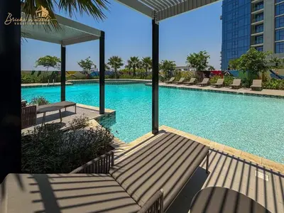 a large swimming pool with lounge chairs in a building at Panorama Sea & Sunset View 2 BHK in Dubai