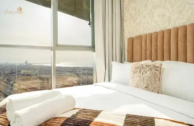 a bedroom with a bed with a large window at Panorama Sea & Sunset View 2 BHK in Dubai