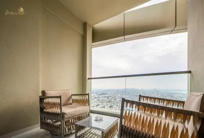 a room with a chair and a table and a large window at Panorama Sea & Sunset View 2 BHK in Dubai