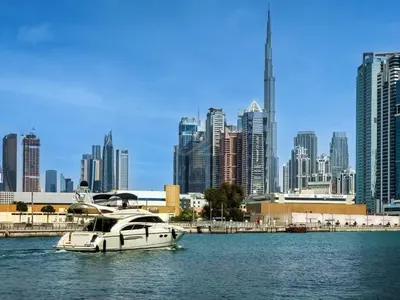 a white boat in the water in front of a city at Brand new 1BD apartment in Canal Front Residence in Dubai
