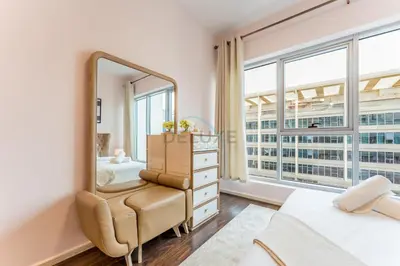 a bedroom with a mirror and a bed and a chair at Affordable Living 1BR, Steps from Retail Stores, Skycourts Tower D, Dubailand by Deluxe Holiday Homes in Dubai