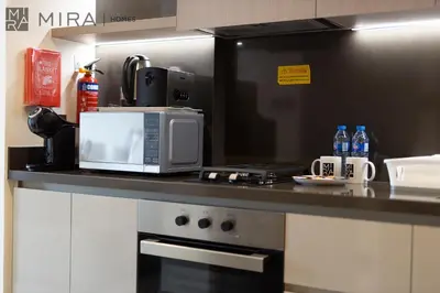 a kitchen with a counter with a microwave and a stove at Mira Holiday Homes - Bright studio with Burj Khalifa view in Business Bay in Dubai