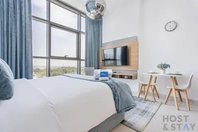 a bedroom with a bed and a table with a laptop on it at Elegant Studio Without Balcony- Damac Hills, Dubai - Host & Stay in Dubai