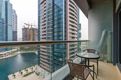 a balcony with a table and chairs and a view of a city at Full Lake View - 1BR Apartment in Goldcrest Views,Cluster V,JLT - Allsopp & Allsopp in Dubai