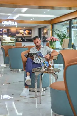 a man sitting in a chair reading a magazine at Golden Sands Bur Dubai in Dubai