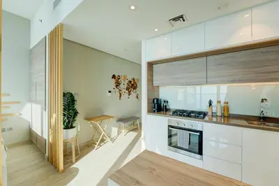 a kitchen with white cabinets and a wooden table at HiGuest - New! Stunning sea view studio, Balcony, Pool in Dubai