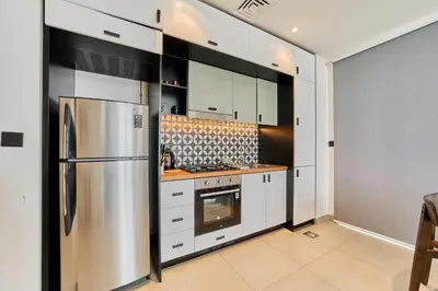a kitchen with white cabinets and a stainless steel refrigerator at Bright & Trendy 2BR in Collective, Dubai Hills in Dubai