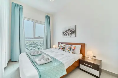 a bedroom with a bed and a window with blue curtains at Bright & Trendy 2BR in Collective, Dubai Hills in Dubai