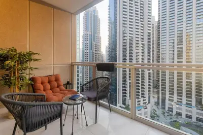 a balcony with a couch and a table and chairs at 2-Bedroom Apartment with Full Burj Khalifa & Opera House Views Just 9 Min Walk to Dubai Mall! in Dubai