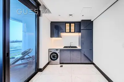 a kitchen with black cabinets and a washer and dryer at Terraces Marasi Drive, Business Bay in Dubai