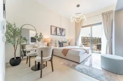 a bedroom with a bed and a table and a dining room at Community Views Studio Near Nad Al Sheba Gardens with Balcony, MAG 980, Mohammad Bin Rashid by Deluxe Holiday Homes in Dubai
