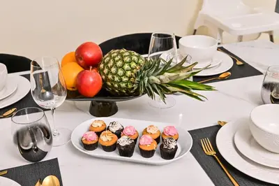 a table with a plate of cupcakes and a pineapple at New Luxury 2 Bedroom with Burj Khalifa View & Spectacular Rooftop Infinity Pool Bar in Dubai