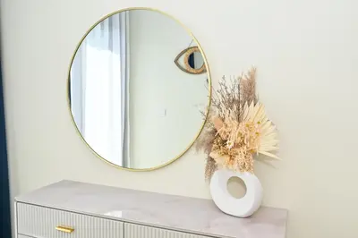 a mirror on a white wall next to a vase on a table at New Luxury 2 Bedroom with Burj Khalifa View & Spectacular Rooftop Infinity Pool Bar in Dubai