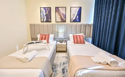two beds in a room with blue curtains at New Luxury 2 Bedroom with Burj Khalifa View & Spectacular Rooftop Infinity Pool Bar in Dubai